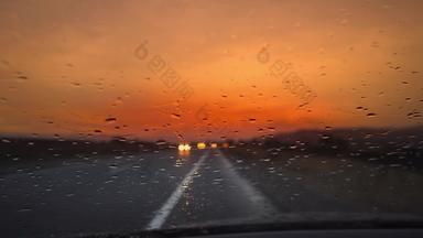 开车车雨路狂风暴雨的挡风玻璃旅行交通多雨的一天橙色日落天空汽车视图观点